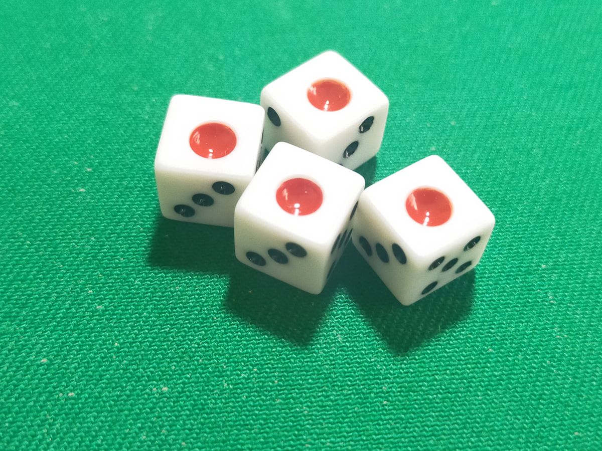 Empat dadu mahjong dengan titik satu merah di atas kain hijau, gambar muka depan soalan lazim mahjong ini